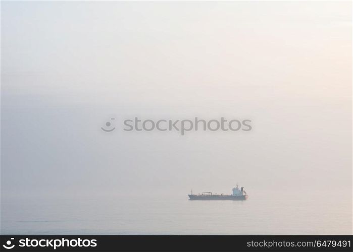 Fine art minimalist image of container ship at sea during foggy . Fine art minimalist landscape image of container ship at sea during foggy morning giving appearance of ship floating