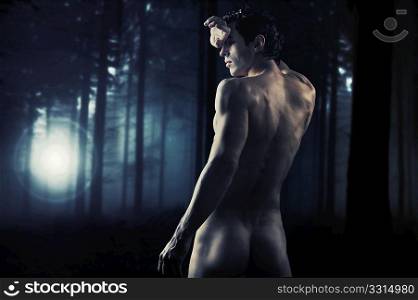 Fine art photo of a young muscular man in a forest