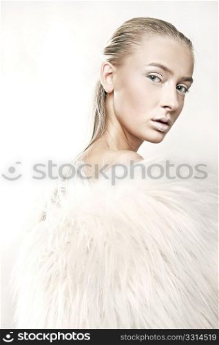 Fine art portrait of a beautiful blonde in white fur