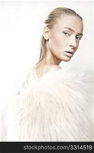 Fine art portrait of a beautiful blonde in white fur