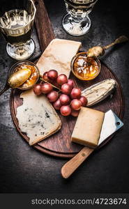 Fine cheese selection with wine, Honey mustard sauce and grape on round rustic cutting board