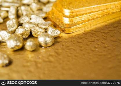 fine gold ingots and nuggets on a wet golden background