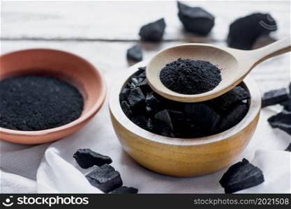 Finely crushed charcoal put in a spoon and a wooden cup.