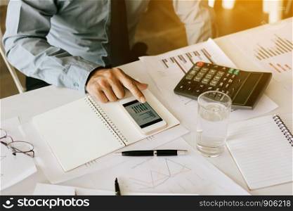 Finger businessman using smartphone with analysis summary chart on desk.