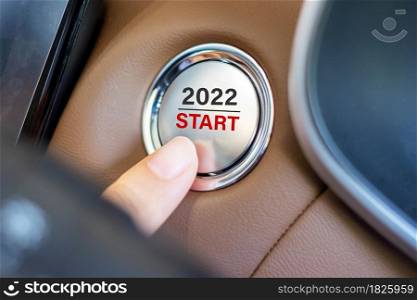 Finger press a car ignition button with 2022 START text inside modern electric automobile. New Year New You, resolution, change, goal, vision, innovation and planning concept