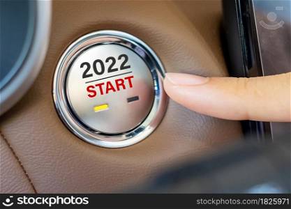 Finger press a car ignition button with 2022 START text inside modern electric automobile. New Year New You, resolution, change, goal, vision, innovation and planning concept