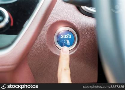 Finger press a car ignition button with 2023 START text inside  automobile. New Year New You, forecast, resolution, motivation, change, goal, vision, innovation and planning concept