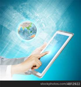 Finger touch. Close up image of human hand touching screen of tablet pc. Elements of this image are furnished by NASA