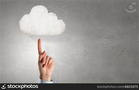 Finger touching cloud. Close up of hand pointing with finger at white cloud