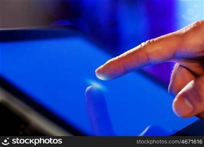 Finger touching screen. Close-up image of finger touching blue screen