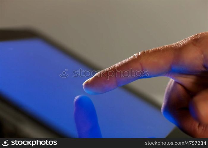 Finger touching screen. Close-up image of finger touching blue screen