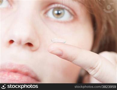 finger with corrective lens close up and female face backhround