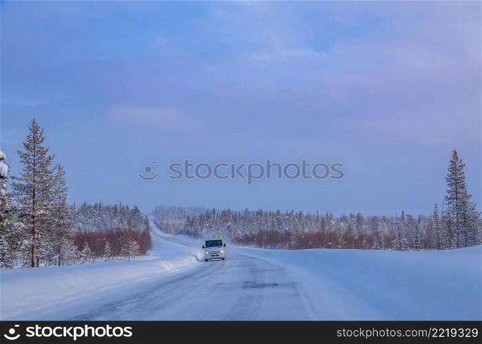 Finnish Lapland. Winter forest road at sunset. Lonely bus. Bus on the Winter Forest Road