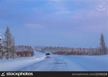 Finnish Lapland. Winter forest road at sunset. Lonely bus. Bus on the Winter Forest Road