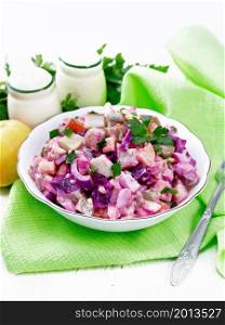 Finnish salad Rosoli of herring, beet, potatoes, pickles, carrots, onions and eggs, dressed with mayonnaise in a bowl on wooden board background