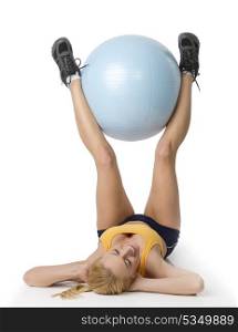 fintness young girl laying down and doing exercise keeping a big ball between legs
