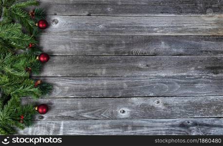 Fir tree branches and red ball ornaments on rustic wooden plank background for a merry Christmas or happy New Year holiday celebration concept