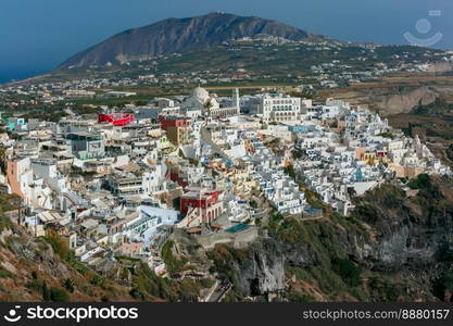 Fira, modern capital of the Greek Aegean island, and Profitis Ilias Mountains, Santorini, in the summer day, Greece. Fira, main town of Santorini, Greece