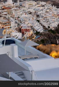 Fira, Santorini, Greece - June 27, 2021: Illuminated balcony decks and patios with restaurants of Fira town on Santorini island. Cyclades, Greece. Illuminated balcony decks and patios with restaurants of Fira town on Santorini island.