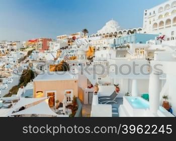 Fira, the capital of Santorini island. The white houses, terraces and Orthodox Cathedral on the steep slope of rocks at sunset.