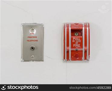 Fire alarm pull station on white cracked wall