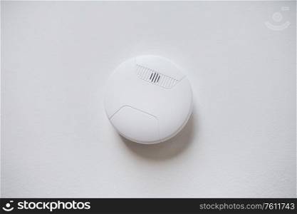 fire alarm system, safety and security concept - domestic smoke detector or sensor on white ceiling. smoke alarm, sensor or detector on white ceiling