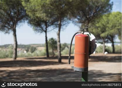Fire extinguisher in the woods. Trees on the background