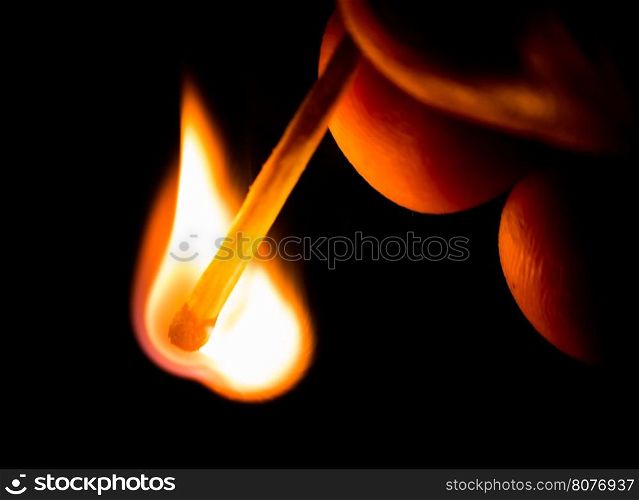 Fire from match in darkness. Hand holding match