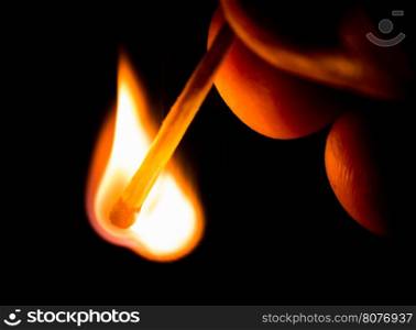 Fire from match in darkness. Hand holding match