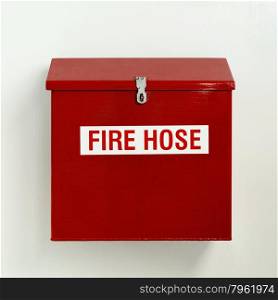 Fire hose box in bright red hung on white wall