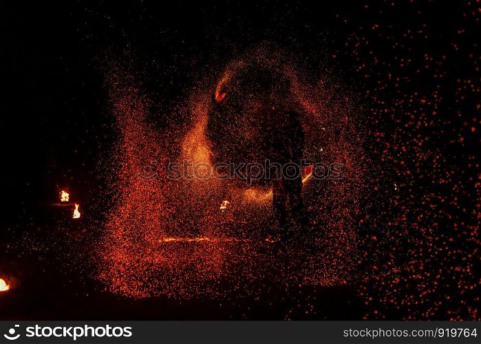 Fire show, dancing with flame, male master juggling with fireworks, performance outdoors, draws a fiery figure in the dark, bright sparks in the night. A man in a suit LED dances with fire.. Fire show, dancing with flame, male master juggling with fireworks, performance outdoors,