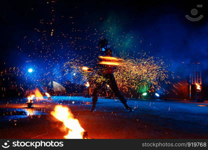 Fire show, dancing with flame, male master juggling with fireworks, performance outdoors, draws a fiery figure in the dark, bright sparks in the night. A man in a suit LED dances with fire.. Fire show, dancing with flame, male master juggling with fireworks, performance outdoors,