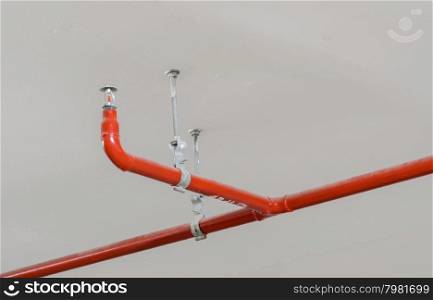 Fire sprinkler and red pipe hanging on white ceiling background