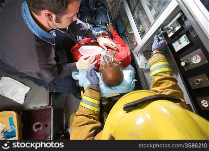 Firefighter and paramedic helping man in ambulance