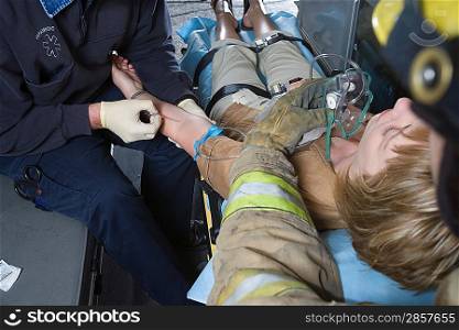 Firefighter and paramedic helping woman in ambulance