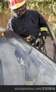 Firefighter cutting out a windshield after an accident