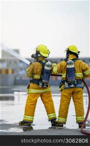 Firefighter or fireman team work water spray by high pressure nozzle to fire.