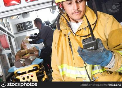 Firefighter using radio, paramedic tending victim