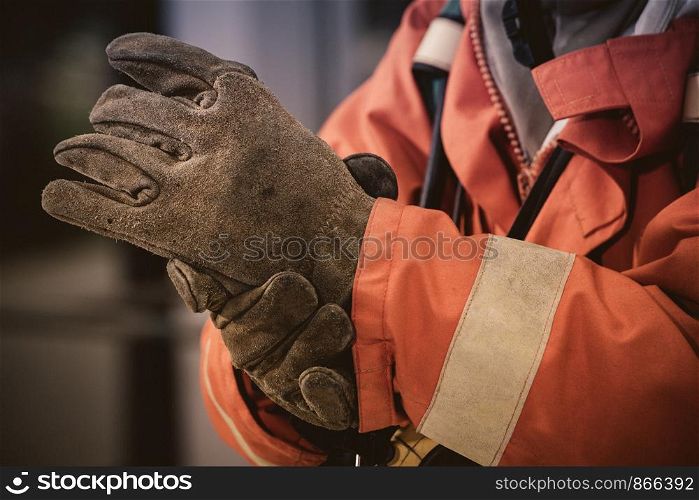 Firefighter wearing glove and safety suite for fire fighting on white background, fire safety concept