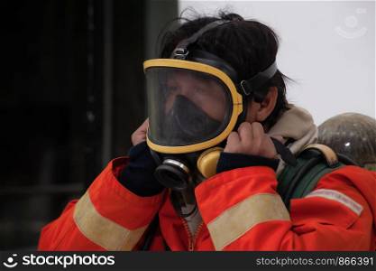 Firefighter wearing mask and safety suite for fire fighting on white background, fire safety concept