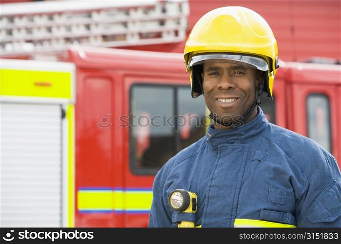 Fireman standing by fire engine wearing helmet