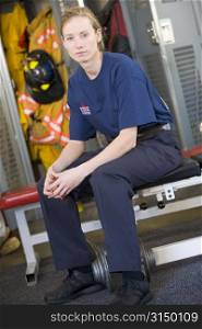 Firewoman sitting on bench in fire station locker room