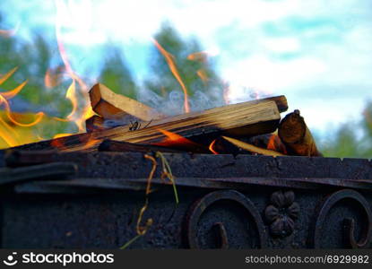 firewood burning on blue sky background in summer. firewood burning on blue sky background in summer, Russia