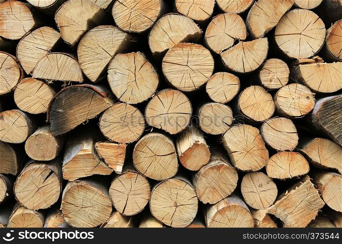 Firewood pile stacked chopped wood trunks, close-up wooden background
