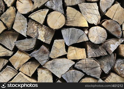 Firewood pile stacked chopped wood trunks, close-up wooden background
