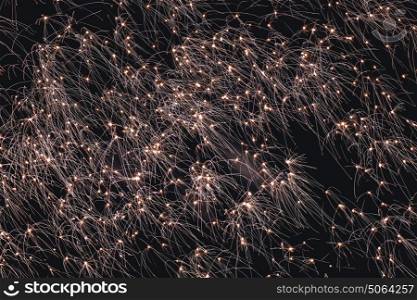 Firework sparkles exploding in bright light in the dark sky at a celebration of new year