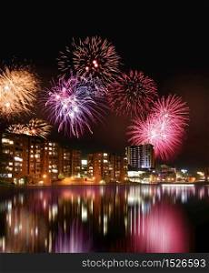Fireworks in the night and colorful city nightline reflecting from water