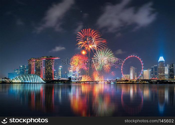 Fireworks of Singapore National Day in Downtown Singapore city in Marina Bay area at night. Financial district, The Ferris Wheel, and skyscraper buildings.
