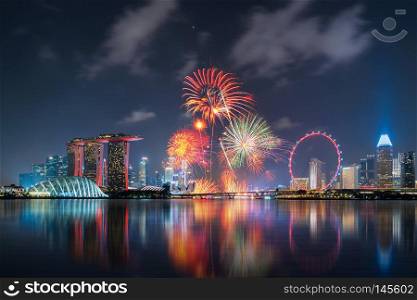Fireworks of Singapore National Day in Downtown Singapore city in Marina Bay area at night. Financial district, The Ferris Wheel, and skyscraper buildings.