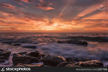 First light. Stunning seascape with motion blur and flowing waves at the rocks